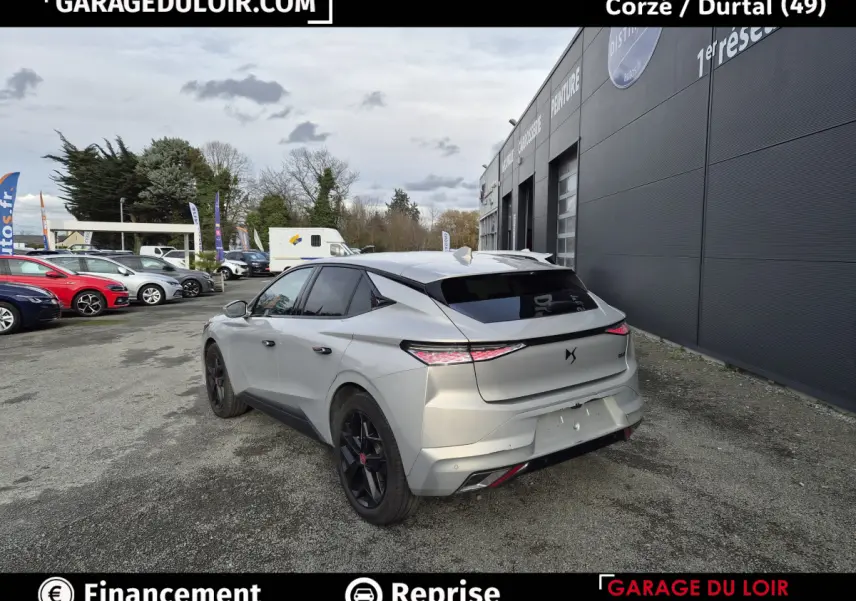 Vue 3/4 arrière droite d'une DS4 beige 2024 avec feux arrière LED et jantes noires, stationnée devant un garage.