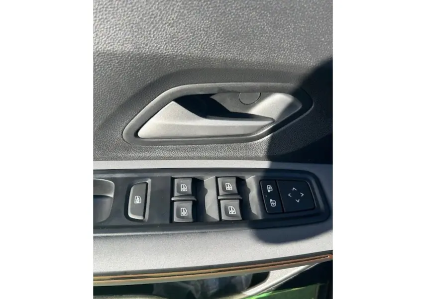 Détail des commandes de lève-vitres et verrouillage sur la porte côté conducteur d'une Dacia Sandero III Stepway noir nacré.