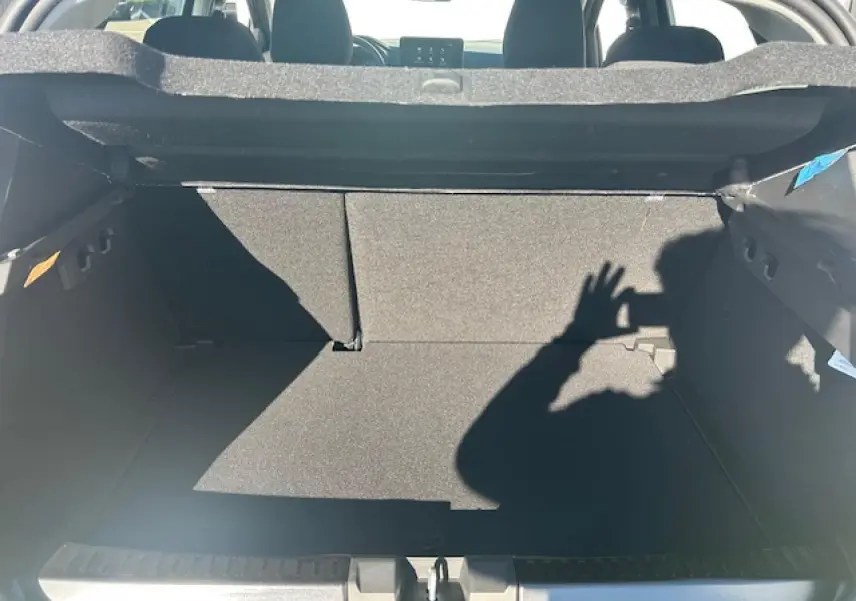 Coffre ouvert vu de l'arrière d'une Dacia Sandero III Stepway noir nacré, intérieur sombre et banquette arrière visible.