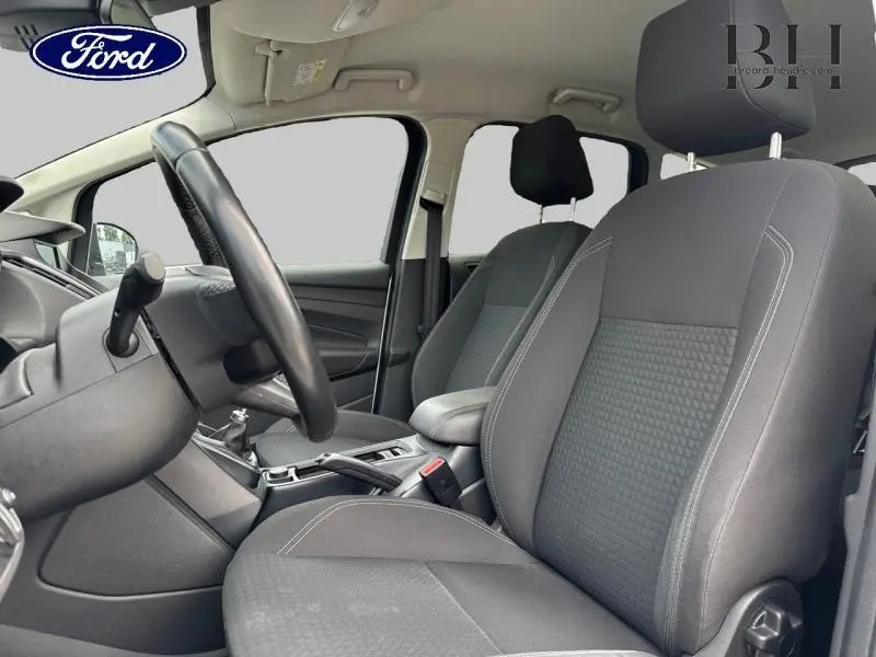 Intérieur avant du Ford C-MAX 2019 avec sièges noirs, volant cuir multifonction et levier de vitesse manuel visible côté gauche.