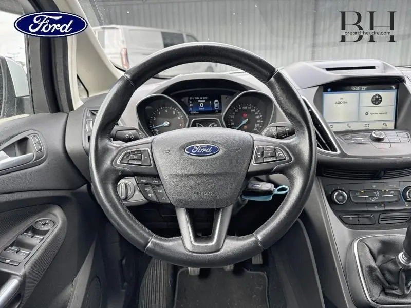 Vue intérieure du volant cuir multifonction et tableau de bord du Ford C-MAX blanc Glacier avec écran tactile et commandes au volant.