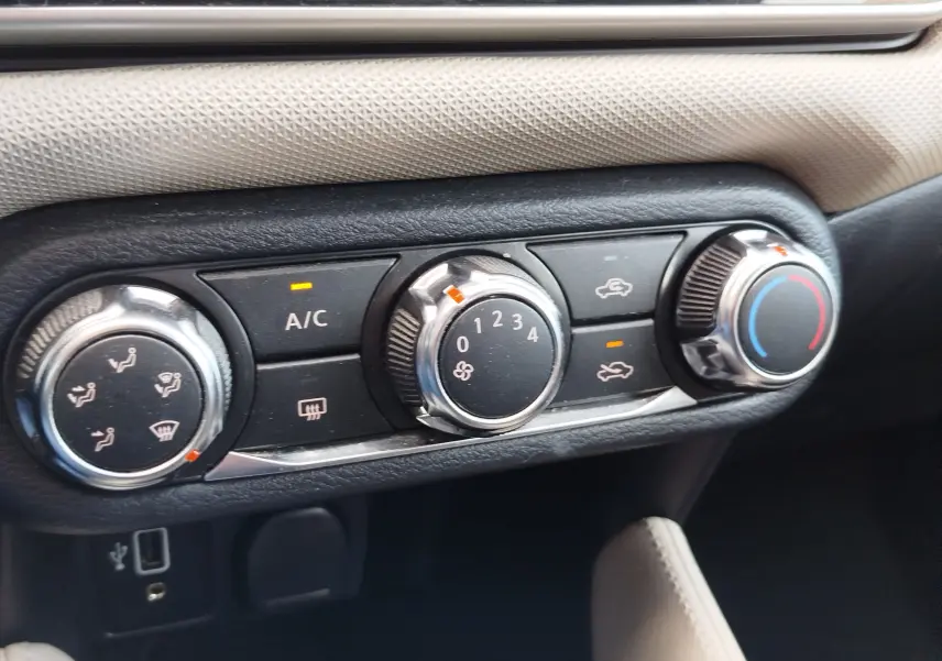 Gros plan sur les commandes de climatisation de la Nissan Micra blanche 2019, avec réglages manuels et voyants allumés.