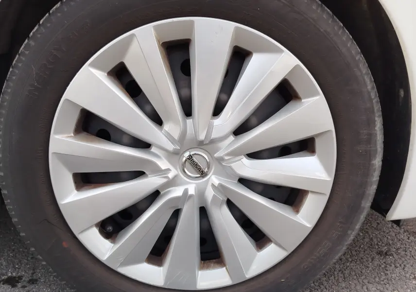 Gros plan sur la jante argentée d'une Nissan Micra blanche de 2019, mettant en valeur le logo central Nissan.