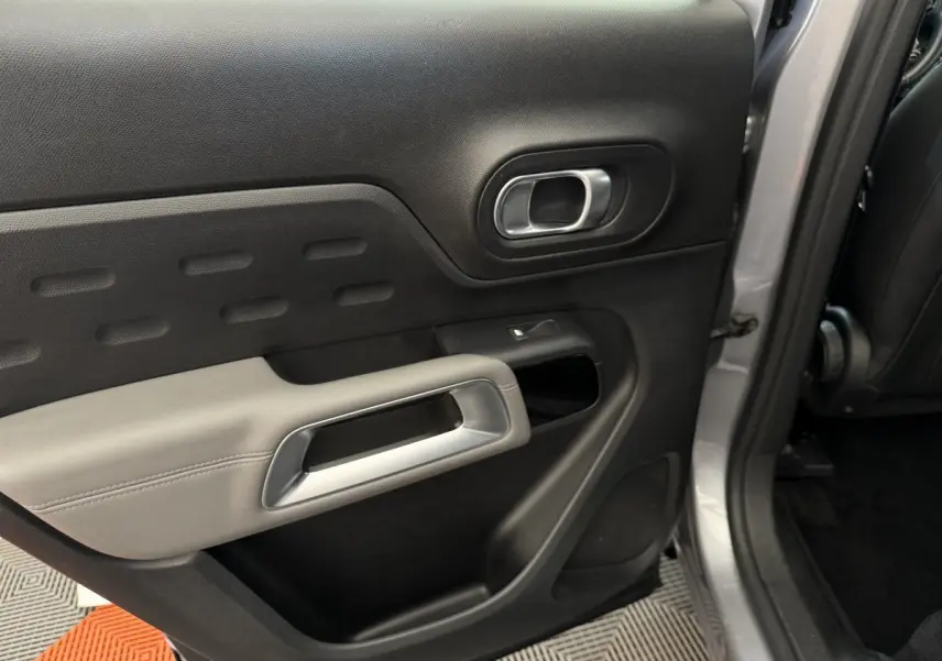 Vue intérieure de la porte arrière droite gris clair du Citroën C5 Aircross avec poignée argentée et accoudoir clair.