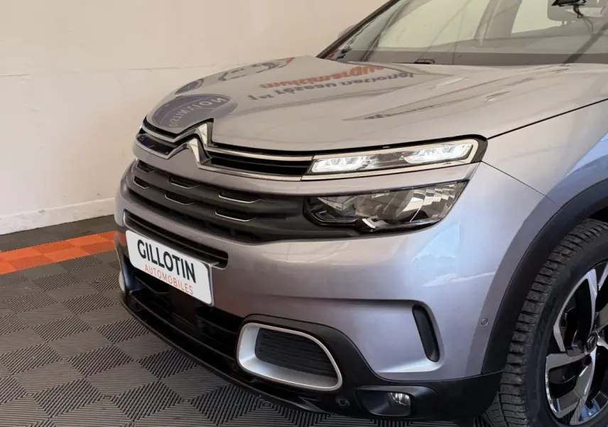 Vue avant droite du Citroën C5 Aircross gris clair, mettant en valeur ses phares LED et la calandre distinctive.