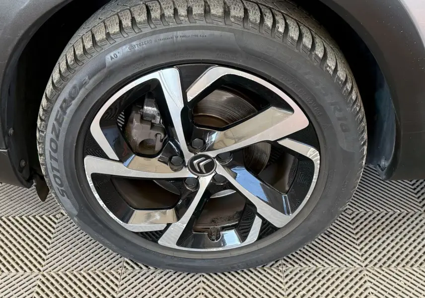 Gros plan sur la roue avant droite du Citroën C5 Aircross gris clair, avec jante alliage noire et argentée au design moderne.