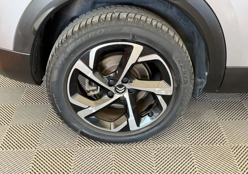 Gros plan sur la roue avant gauche gris clair du Citroën C5 Aircross avec jante alliage bicolore et logo Citroën central.