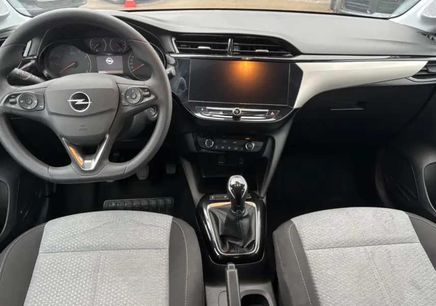 Vue intérieure avant de l’Opel Corsa gris clair 2024, montrant le volant multifonctions, la boîte manuelle et l’écran tactile central.