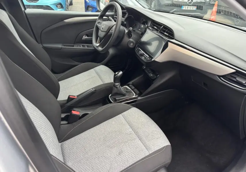 Vue intérieure côté conducteur de l’Opel Corsa gris clair 2024, montrant sièges bi-ton, volant multifonctions et écran tactile.
