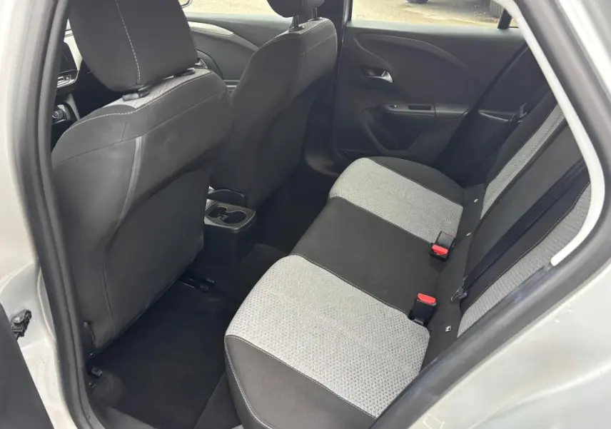 Vue intérieure côté arrière droit de l’Opel Corsa gris clair 2024, sièges arrière bicolores tissu et noir.