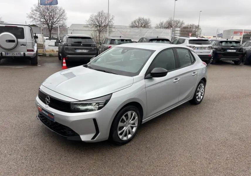 Opel Corsa gris clair vue 3/4 avant droit, avec jantes classiques et rétroviseurs noirs contrastants.