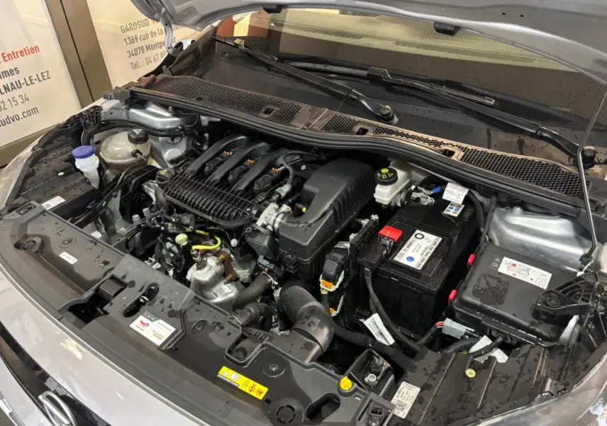 Moteur essence de l’Opel Corsa gris clair 2024 vu de face avec capot ouvert, batterie et composants visibles.