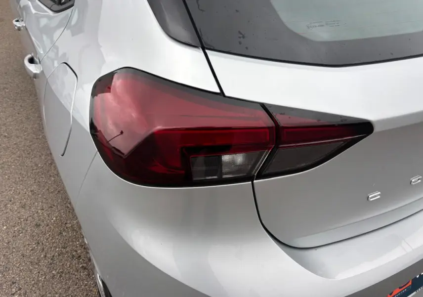 Gros plan sur le feu arrière gauche d’une Opel Corsa gris clair 2024, avec une partie de la malle visible.