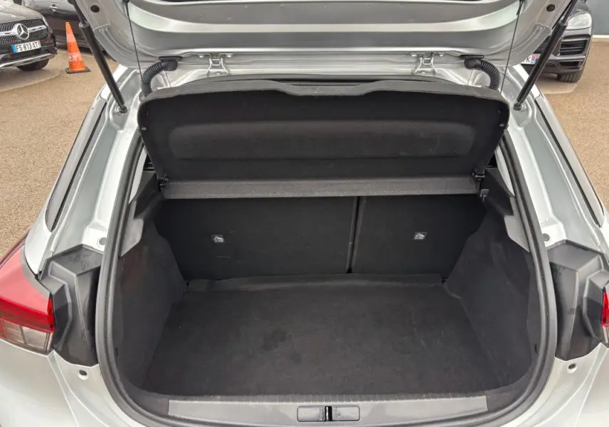 Coffre ouvert vu de l'arrière d'une Opel Corsa gris clair 2024, montrant l'espace de rangement vide.
