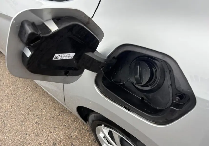 Vue rapprochée du bouchon de réservoir essence ouvert sur le côté gauche d'une Opel Corsa gris clair 2024.