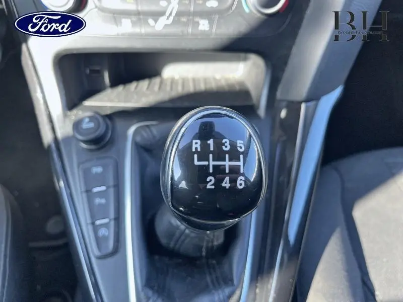 Gros plan sur le levier de vitesses manuel noir de la Ford Focus blanc glacier, avec console centrale et commandes visibles.