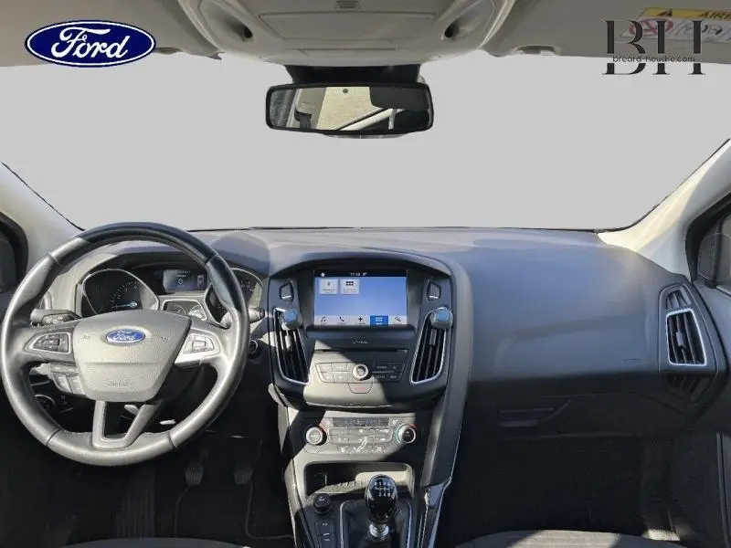 Vue intérieure avant du tableau de bord et volant cuir multifonction de la Ford Focus blanc Glacier avec écran tactile et boîte manuelle.