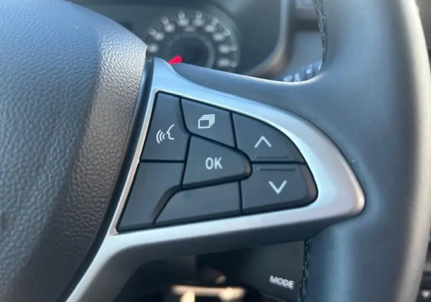 Gros plan sur les commandes multifonctions noires et argent du volant cuir noir du Dacia Sandero III Stepway beige Safari.