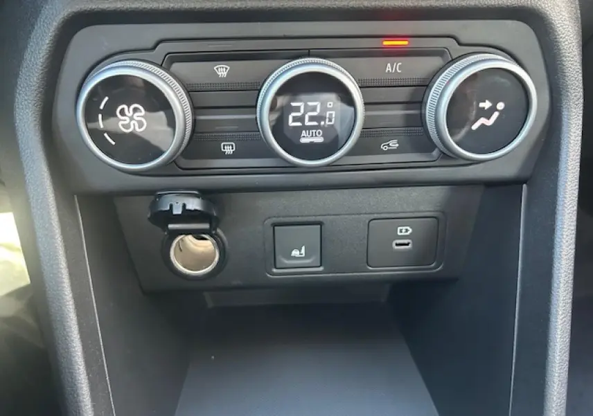 Vue rapprochée du tableau de bord de la Dacia Sandero III Stepway, montrant les commandes de climatisation et prises USB.