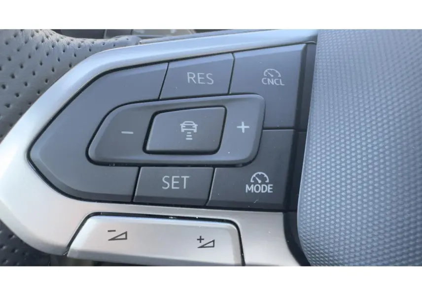 Gros plan sur les commandes du régulateur de vitesse au volant cuir perforé du Volkswagen T-Roc noir, version R-Line.