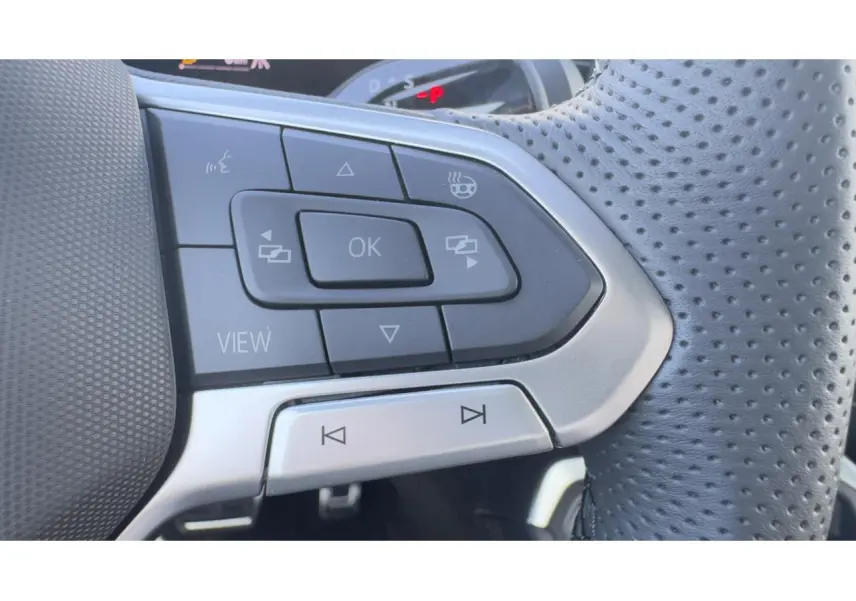 Gros plan sur les commandes multifonctions du volant cuir perforé du Volkswagen T-Roc noir, version R-Line.
