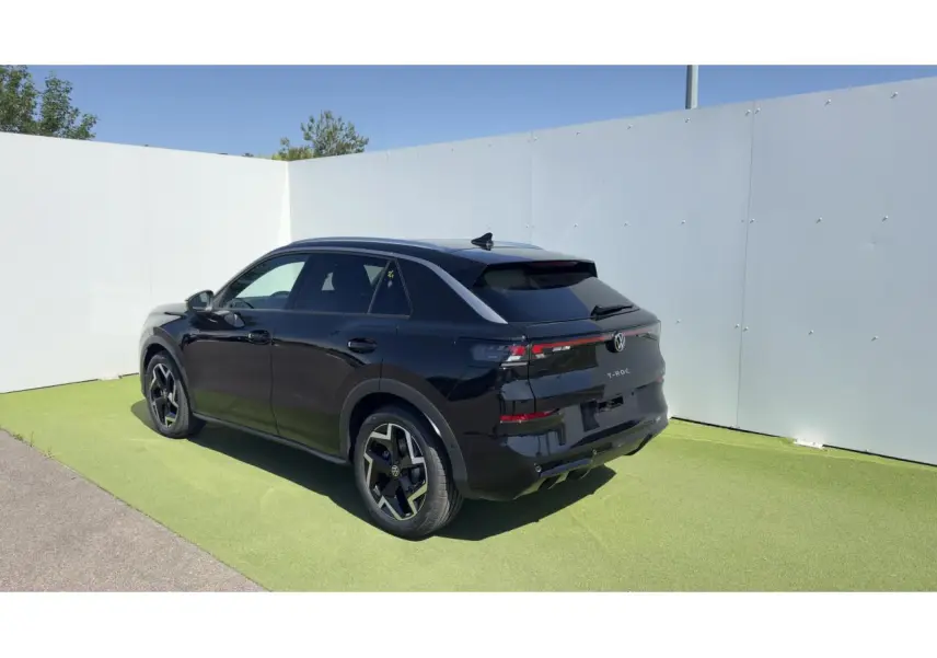 Volkswagen T-Roc noir en 3/4 arrière droit, avec jantes noires et toit ouvrant panoramique visible.