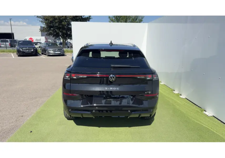 Vue arrière d'un Volkswagen T-Roc noir 2026 avec feux arrière LED reliés par un bandeau lumineux rouge.