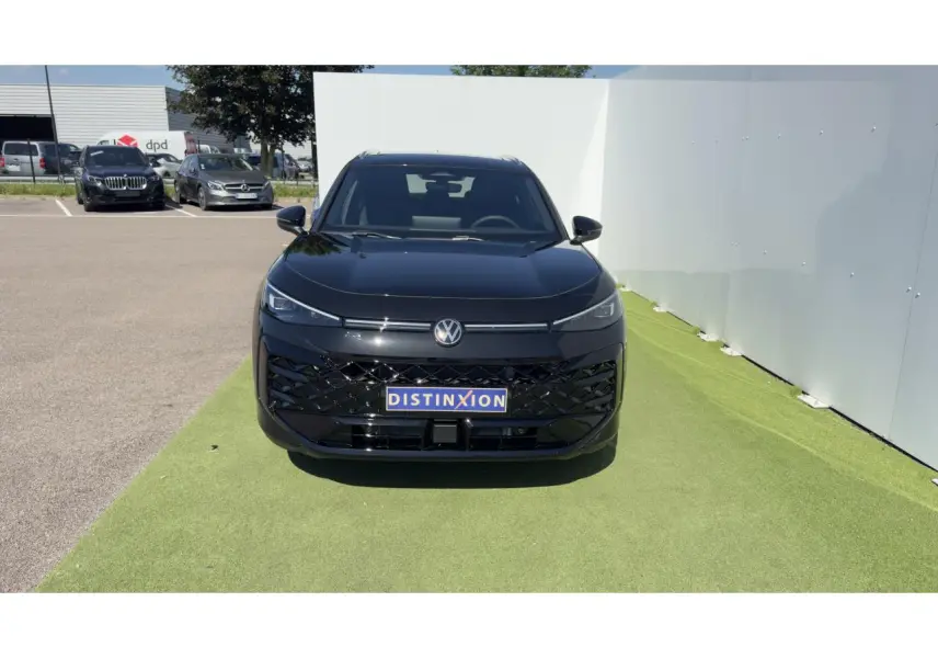 Vue frontale d'un Volkswagen T-Roc noir avec calandre noire brillante et logo VW éclairé sur fond clair.