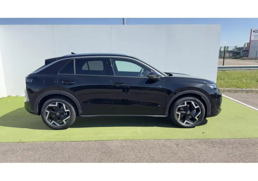 Vue latérale droite d'un Volkswagen T-Roc noir avec jantes 18 pouces et toit noir sur fond extérieur clair.