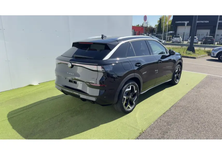 Volkswagen T-Roc noir en 3/4 arrière droit, avec toit noir et jantes 18 pouces Coventry visibles.