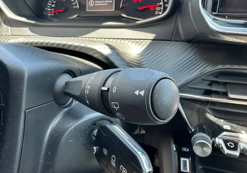 Gros plan sur la commande d’essuie-glace à gauche du volant dans l’habitacle d’une Peugeot 208 gris Artense.
