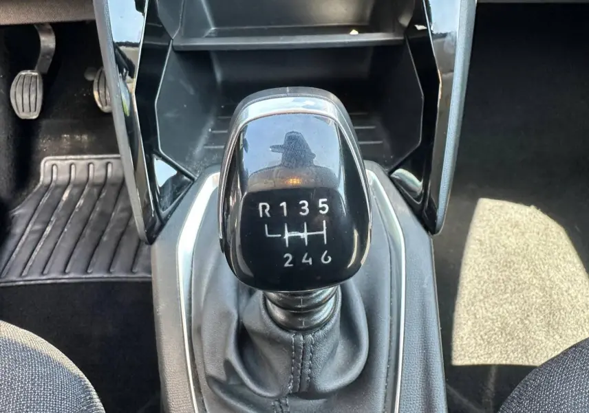Gros plan sur le levier de vitesses manuel noir de la Peugeot 208 gris Artense, entouré de l’intérieur noir.