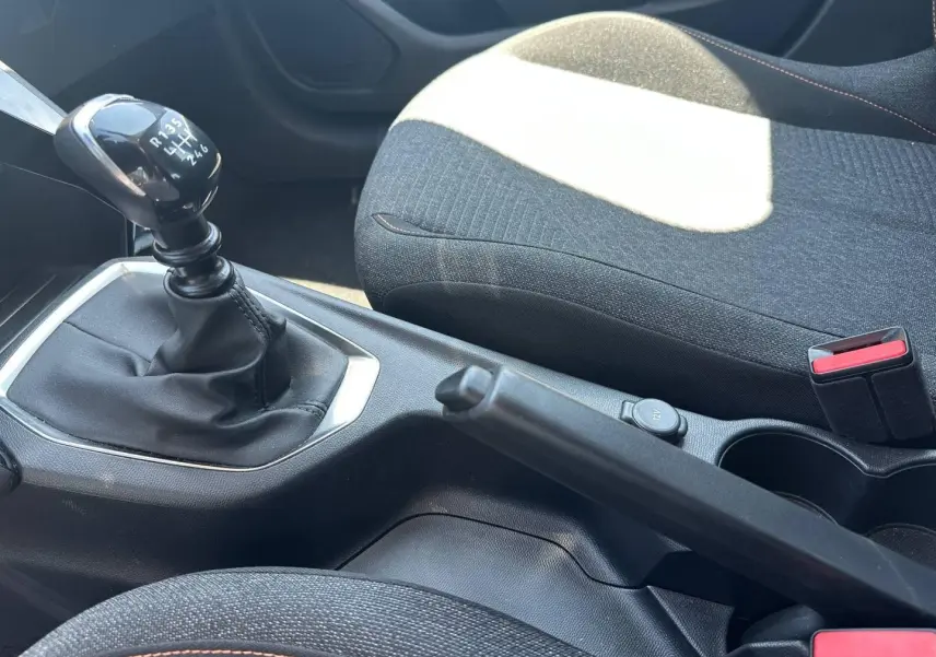 Vue intérieure rapprochée sur la console centrale d’une Peugeot 208 gris Artense avec levier de vitesse manuel et frein à main.
