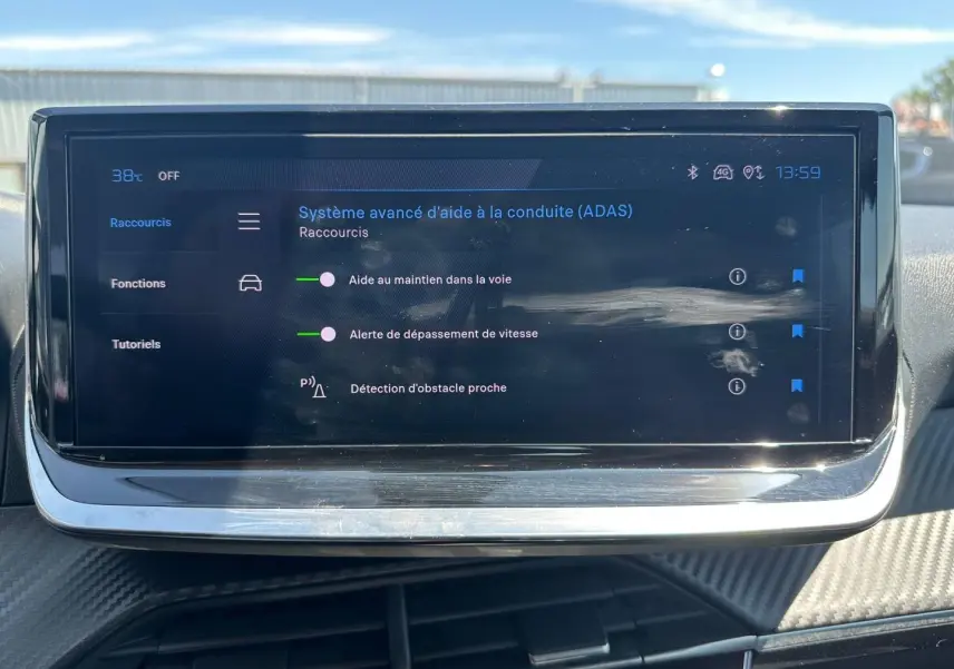 Écran tactile du système d’aide à la conduite sur tableau de bord de Peugeot 208 gris Artense, vue frontale.