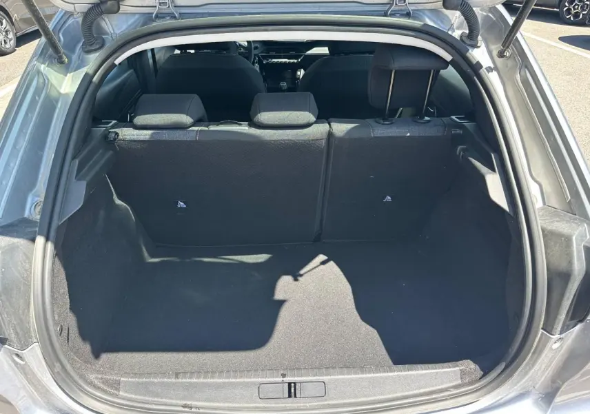 Coffre ouvert vu de l'arrière d'une Peugeot 208 gris Artense, banquette arrière en tissu noir avec surpiqûres visibles.