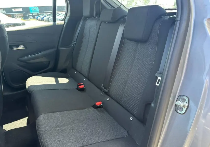 Vue de la banquette arrière côté droit de la Peugeot 208 2025 gris Artense avec tissu noir et ceintures visibles.