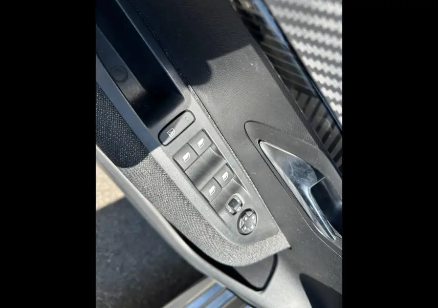 Détail de la porte avant gauche de la Peugeot 208 gris Artense, avec commandes des vitres et rétroviseurs électriques.