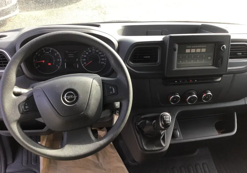 Vue intérieure du tableau de bord et volant noir d'un Opel Movano L3H1 2020 avec boîte manuelle et écran tactile verrouillé.