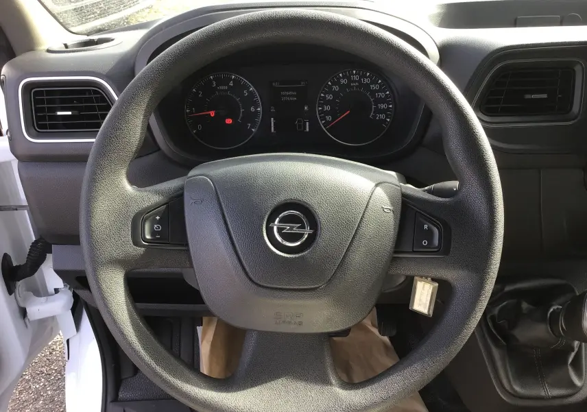 Vue rapprochée du volant noir d'un Opel Movano Chassis Cabine blanc, avec tableau de bord et levier de vitesses manuelle visibles.