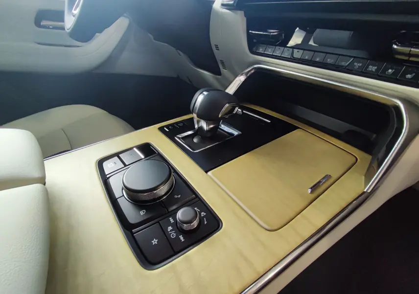 Gros plan sur la console centrale bois clair du Mazda CX-80 2024, avec levier de vitesse et commandes multimédia.