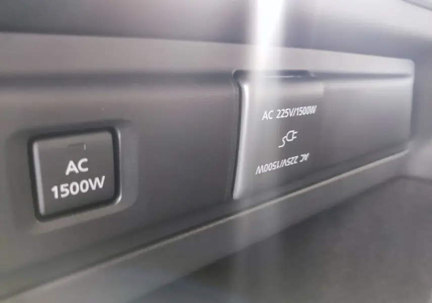 Gros plan sur la prise AC 1500W intégrée dans le tableau de bord du Mazda CX-80 gris foncé 2024 hybride rechargeable.