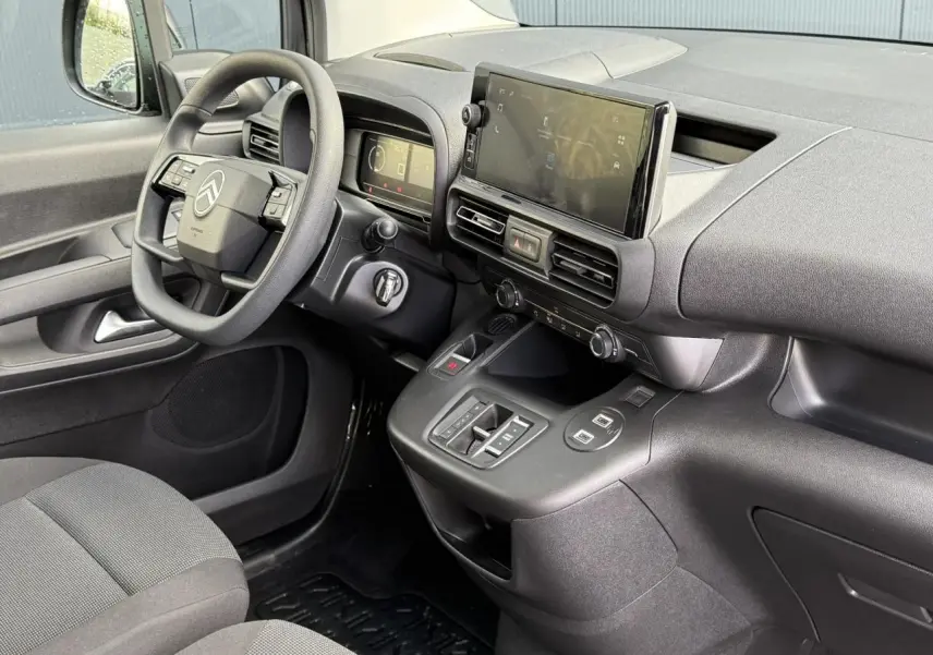 Vue intérieure côté conducteur du Citroën Berlingo 2025 avec tableau de bord noir et écran tactile central.