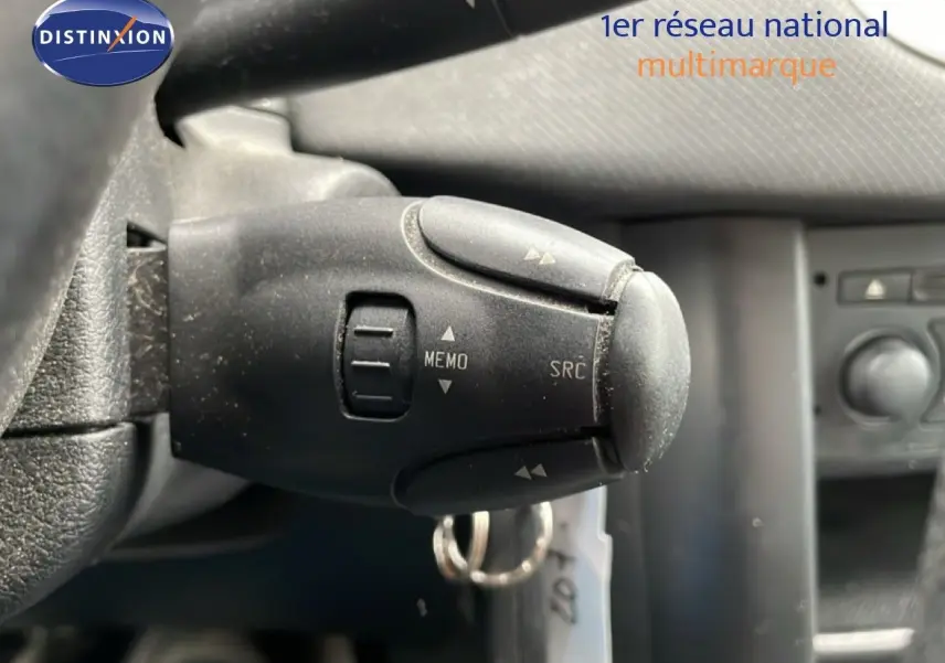 Gros plan sur la commande au volant de la Peugeot 207 rouge métal, montrant les boutons MEMO et SRC.