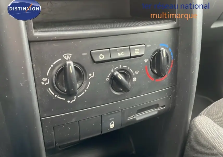 Gros plan sur la console centrale de la Peugeot 207 rouge métal, montrant les commandes de climatisation et ventilation.