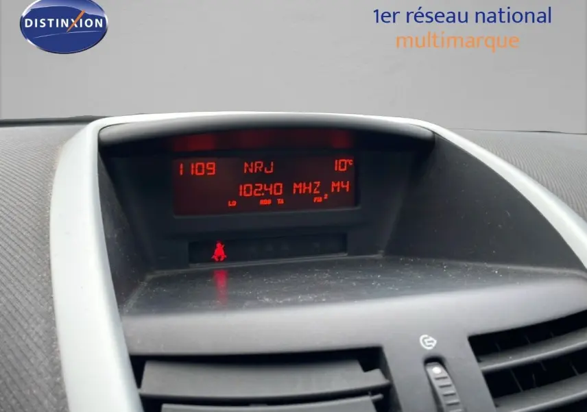 Tableau de bord de Peugeot 207 rouge métal 2009, affichage radio et température, vue intérieure centrée.