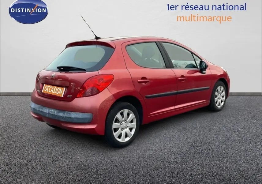 Peugeot 207 rouge métal vue 3/4 arrière côté droit, compacte 5 portes avec jantes alliage et antenne toit.