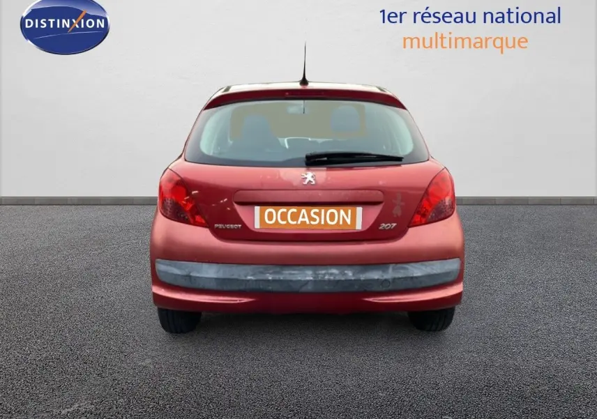 Vue arrière d'une Peugeot 207 rouge métal de 2009, compacte avec hayon et feux arrière rouges.