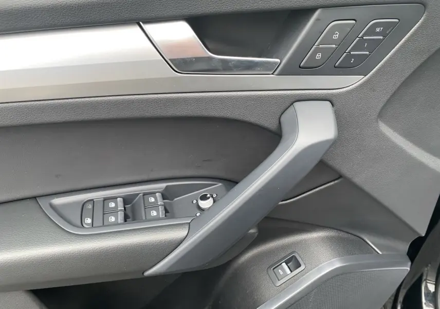Vue rapprochée de la porte avant gauche noire de l'Audi Q5 avec commandes de vitres, verrouillage et réglages mémoire.