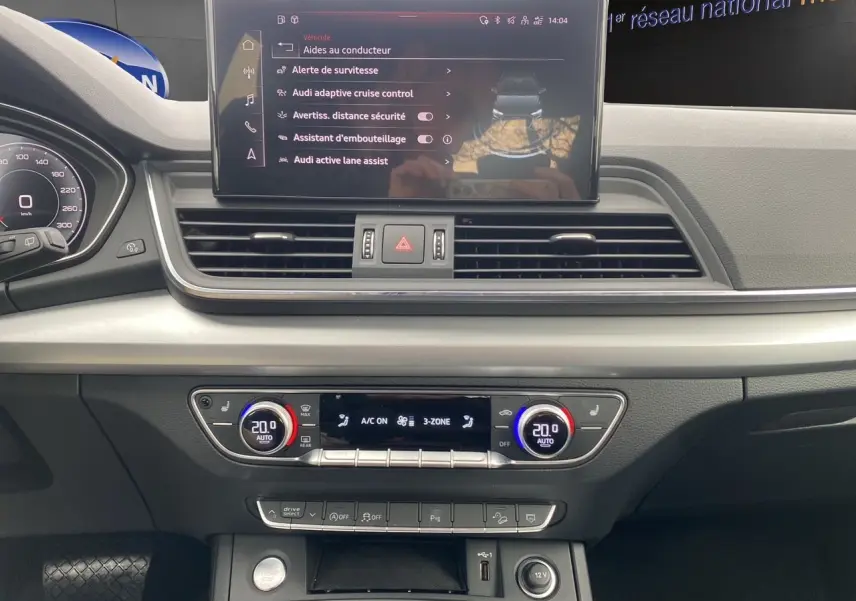 Vue rapprochée du tableau de bord de l'Audi Q5 noir 2022, avec écran tactile et commandes climatisation 3 zones.