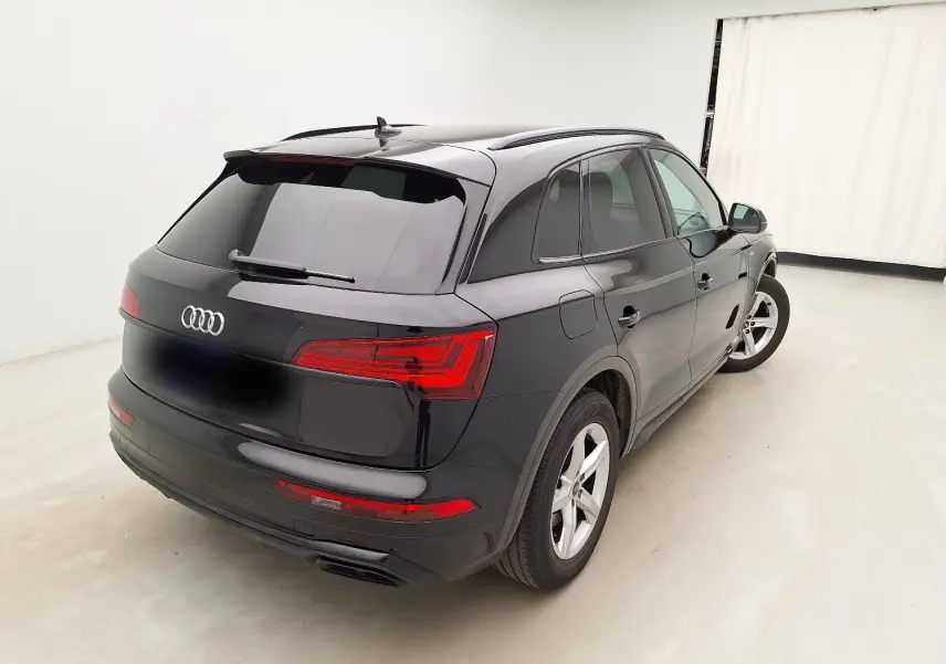 Audi Q5 noir vue 3/4 arrière droit dans un studio, mettant en valeur ses feux LED et son design élégant.